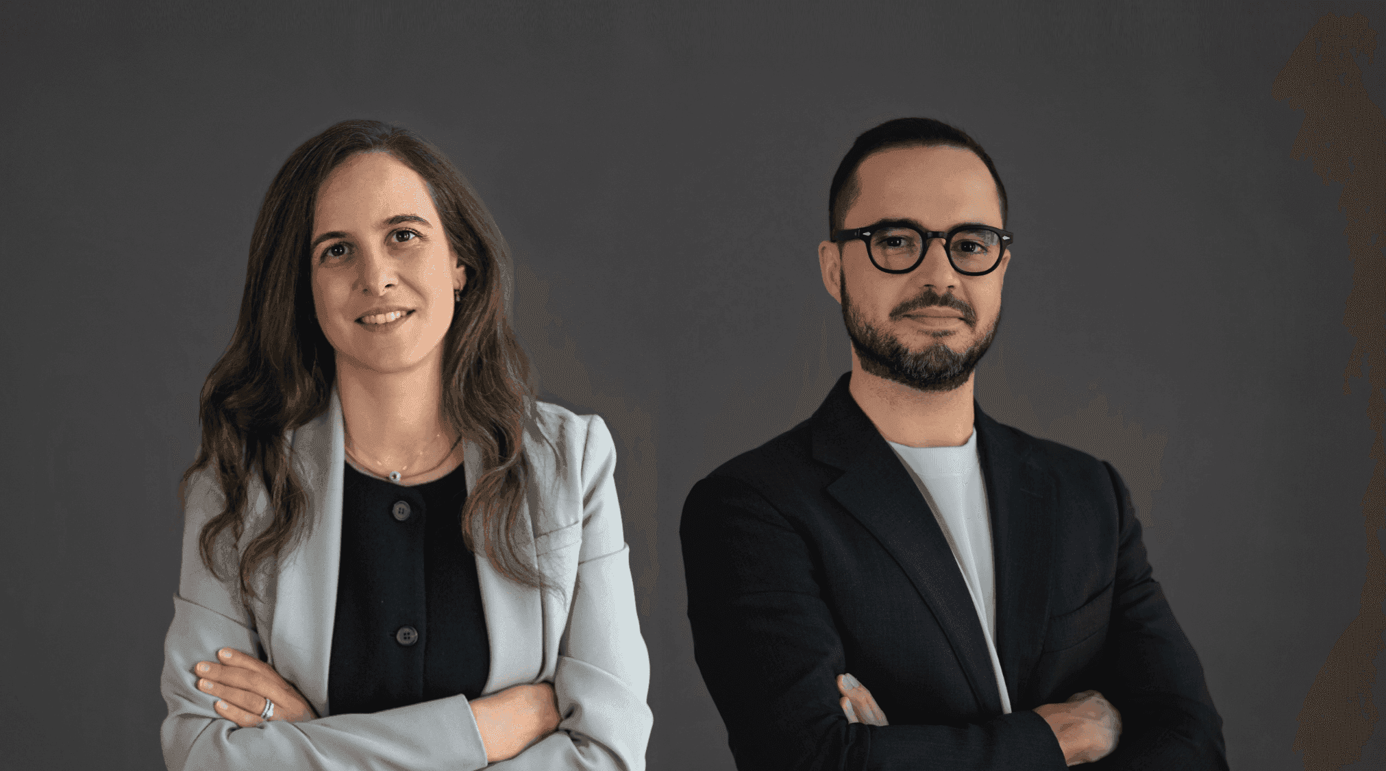 Portrait of a woman and a man standing side by side with their arms crossed.