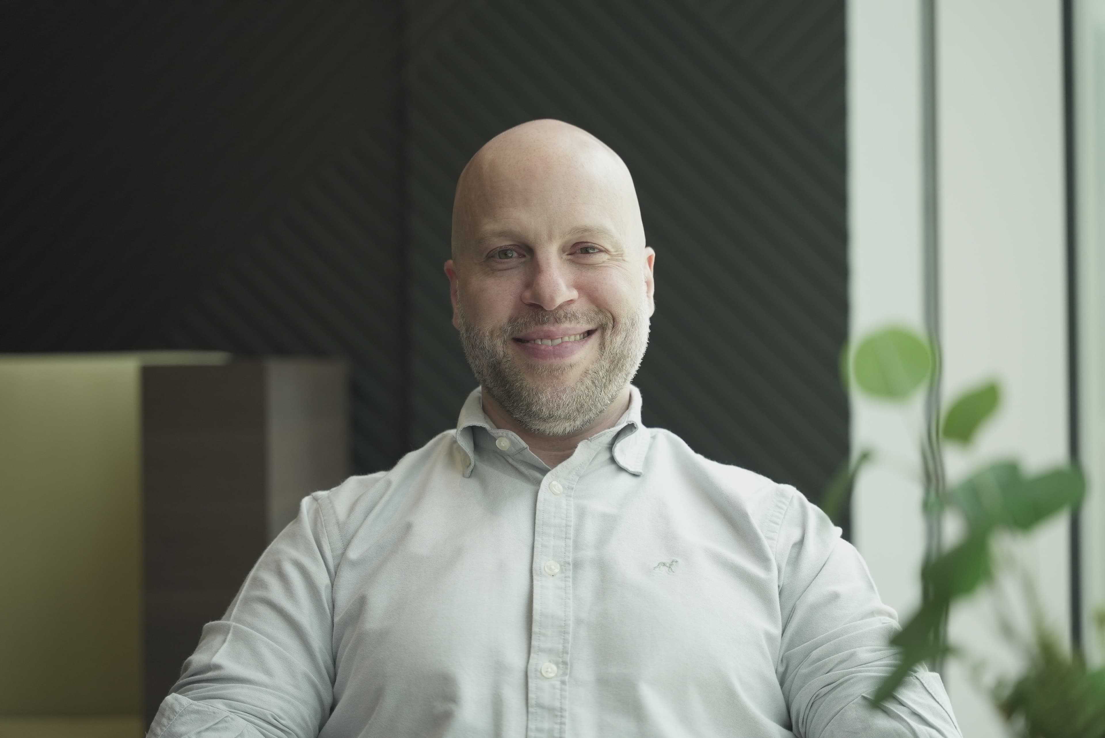 Portrait of a smiling bald man wearing a light-colored shirt.