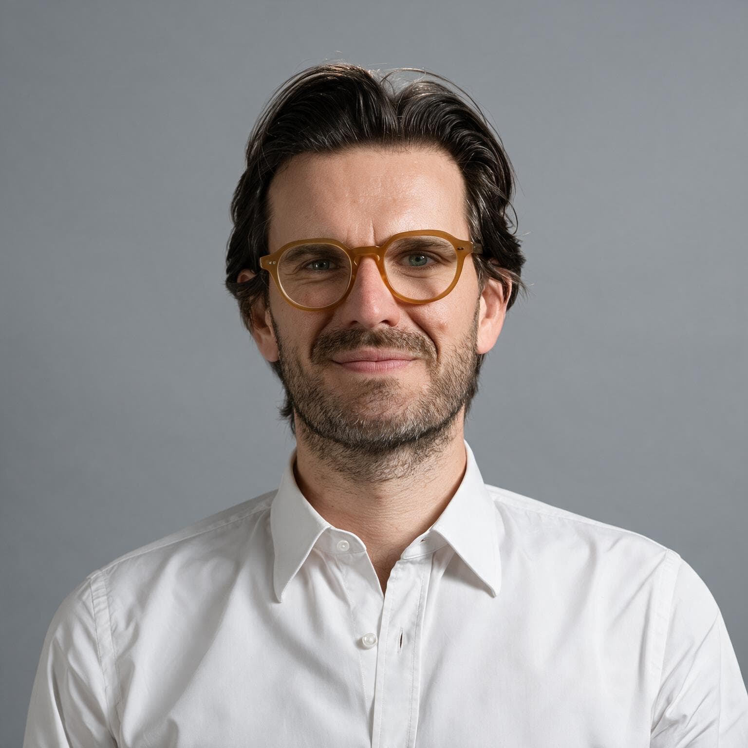 Portrait of a man wearing glasses and a white shirt.