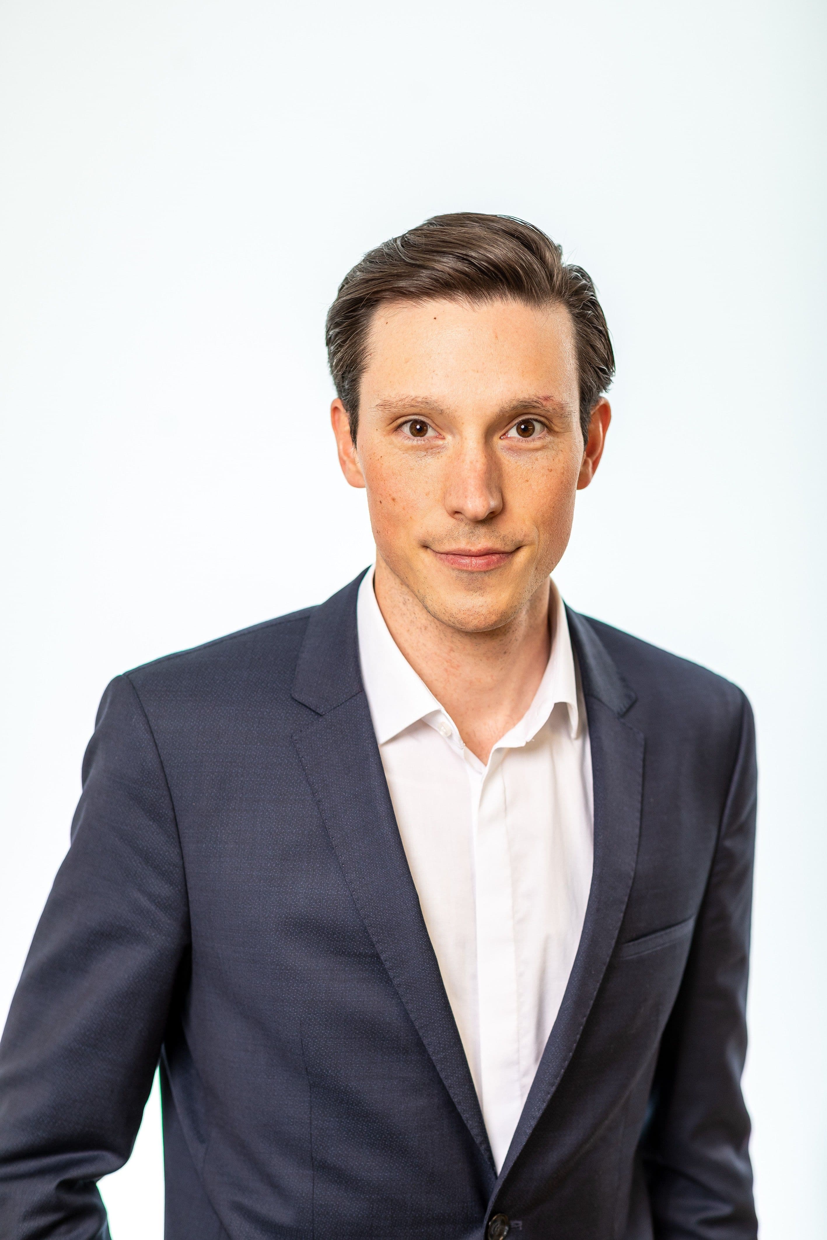 Portrait of a man wearing a dark suit over an open-collared white shirt.