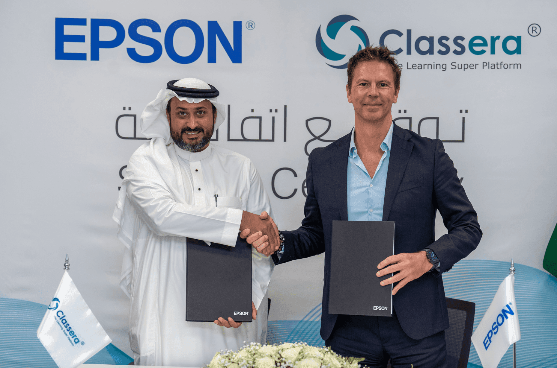 Two men holding agreement folders in front of Epson and Classera branding.
