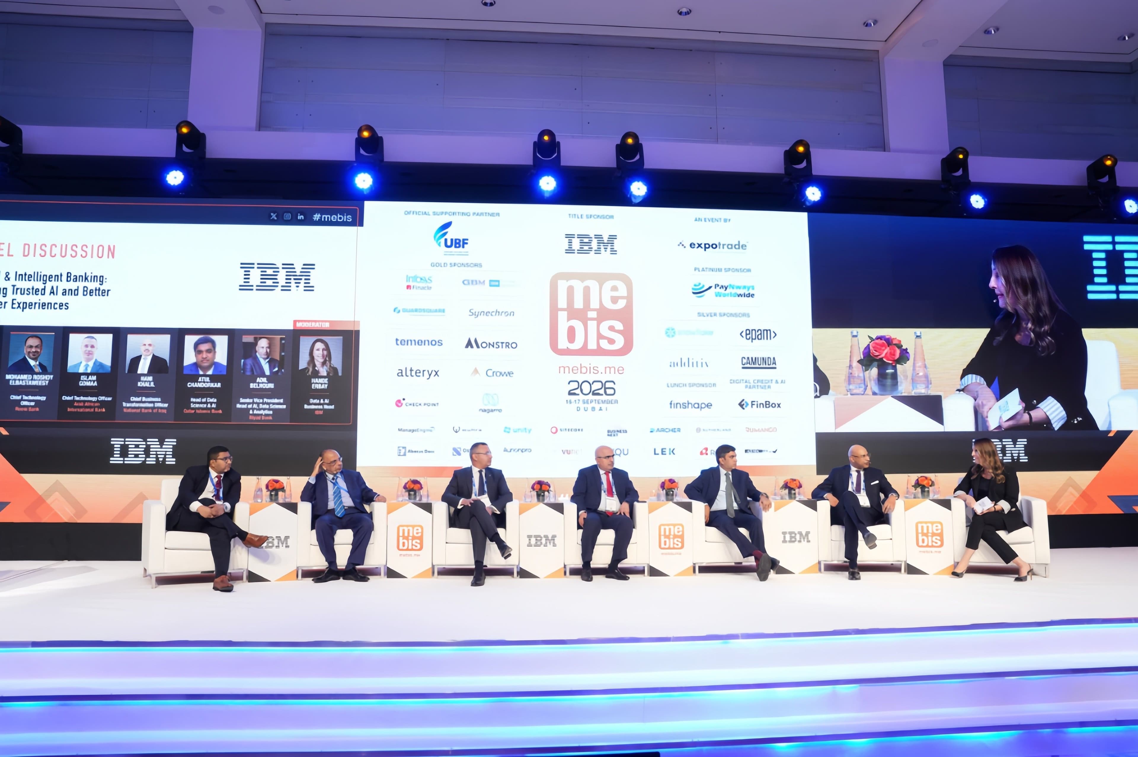Panel discussion on a conference stage with IBM event branding.