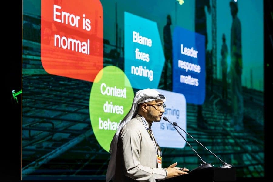 Speaker at a podium beside a screen listing principles for working with errors and uncertainty.