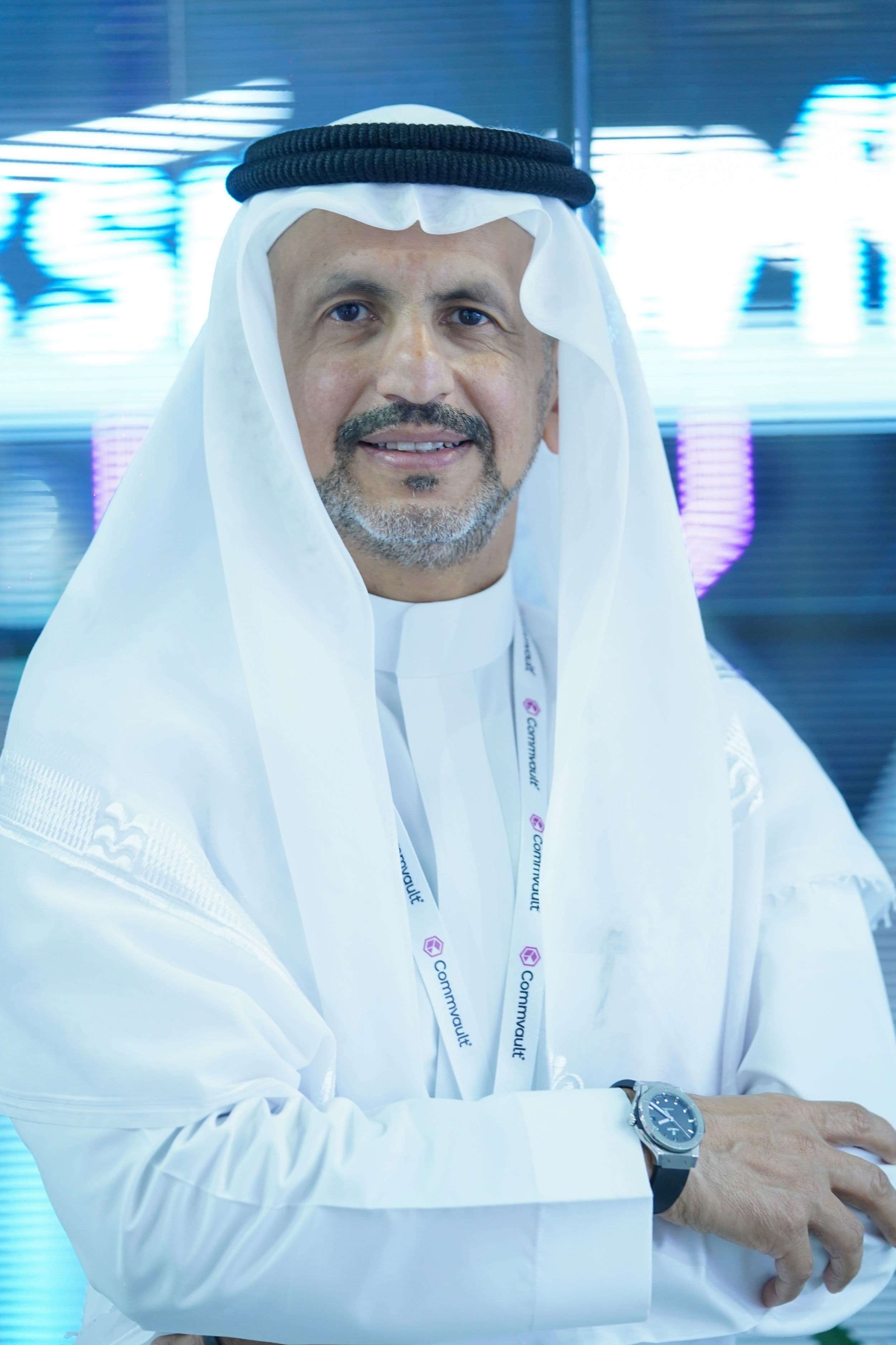 Man wearing traditional Gulf clothing speaking at a microphone.