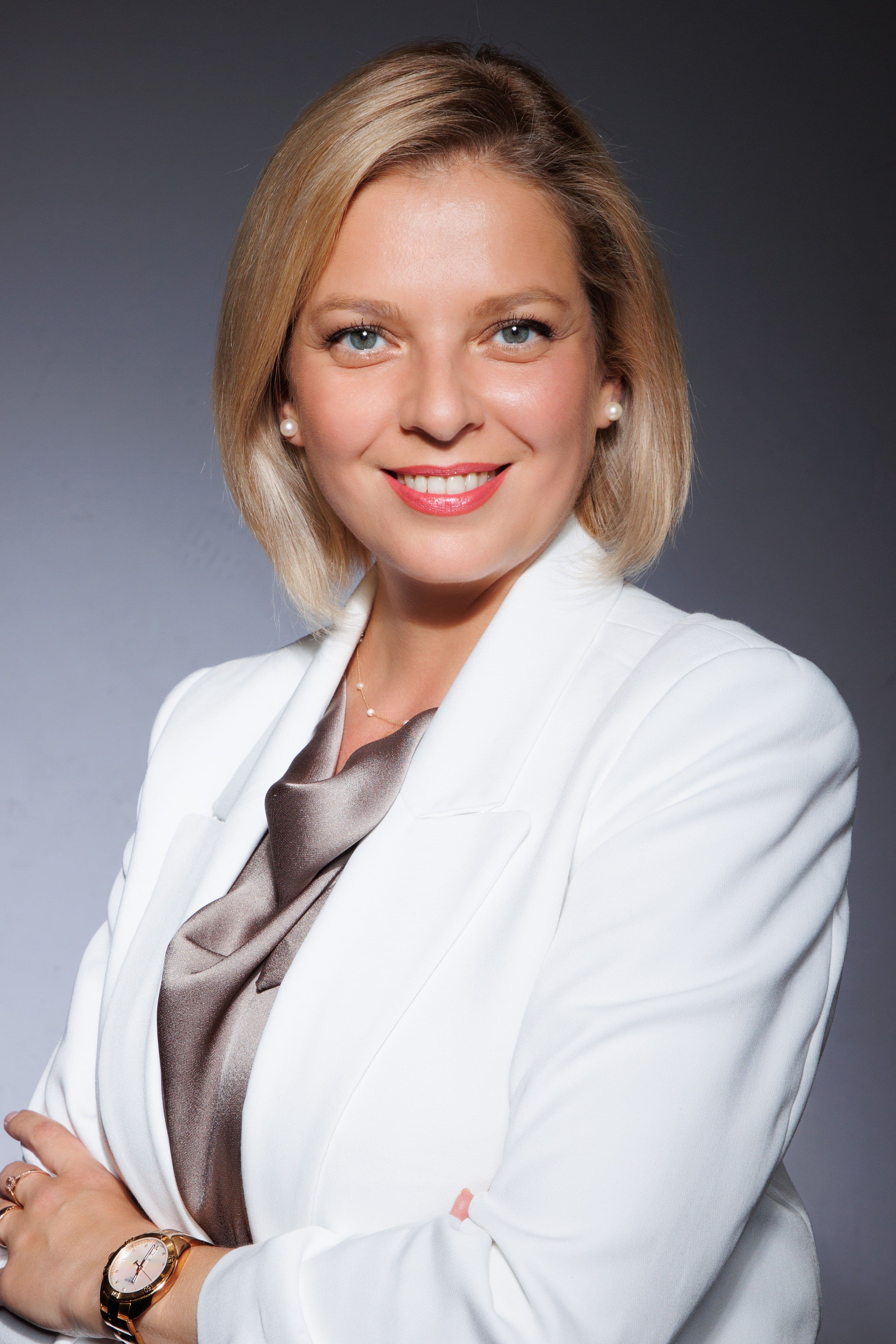 Portrait of a smiling woman wearing a white blazer.