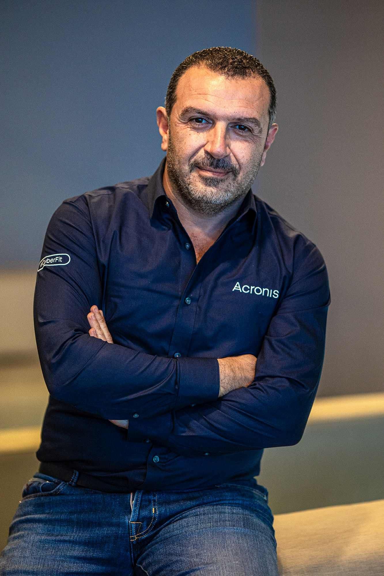 Portrait of a bearded man in a dark shirt standing with his arms crossed.