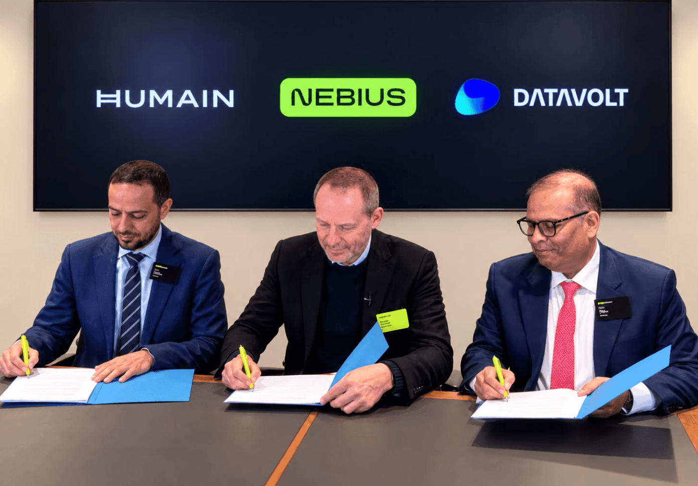 Three representatives signing documents beneath HUMAIN, Nebius, and DataVolt branding.