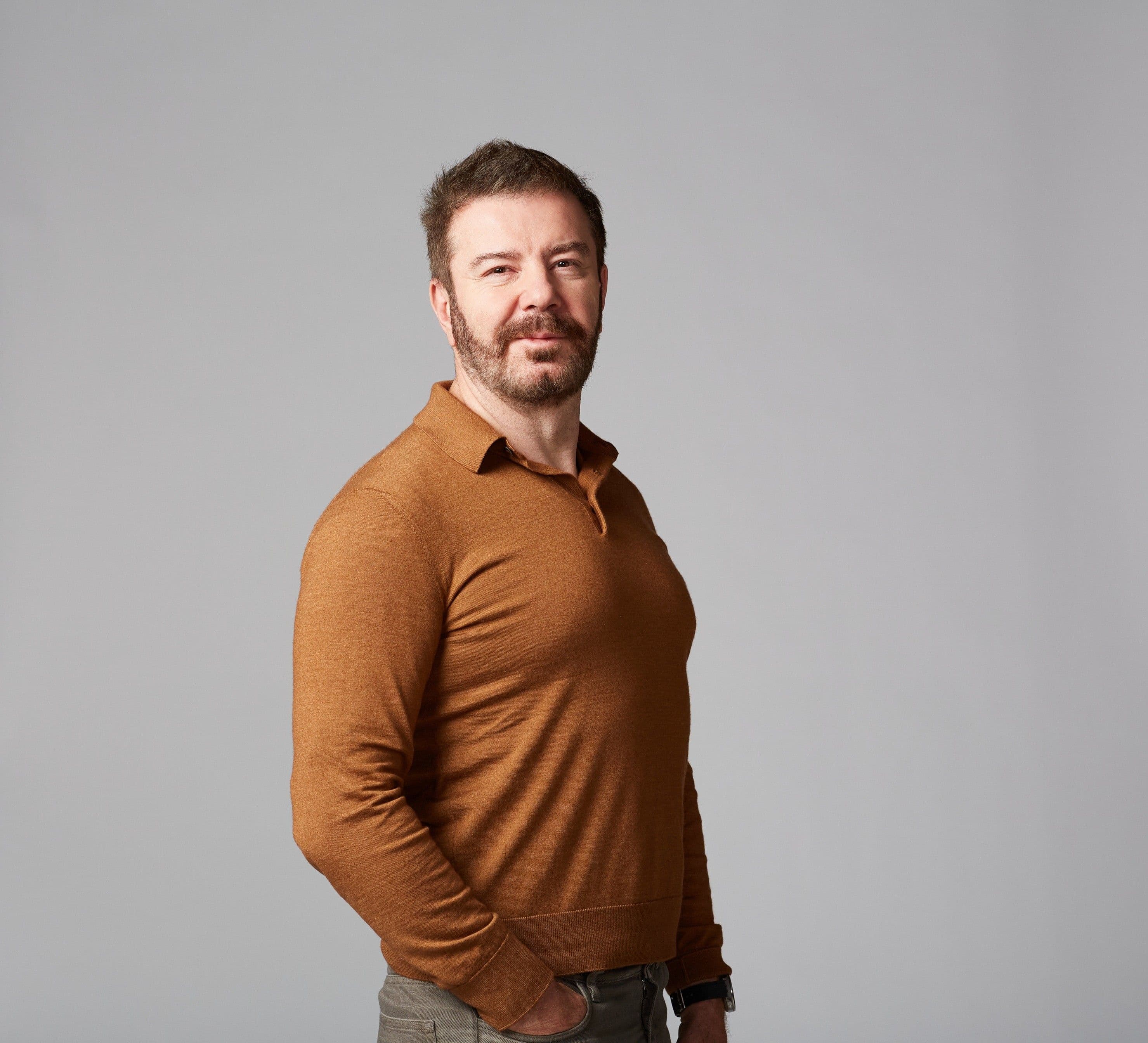 Portrait of a man wearing a brown long-sleeved shirt.