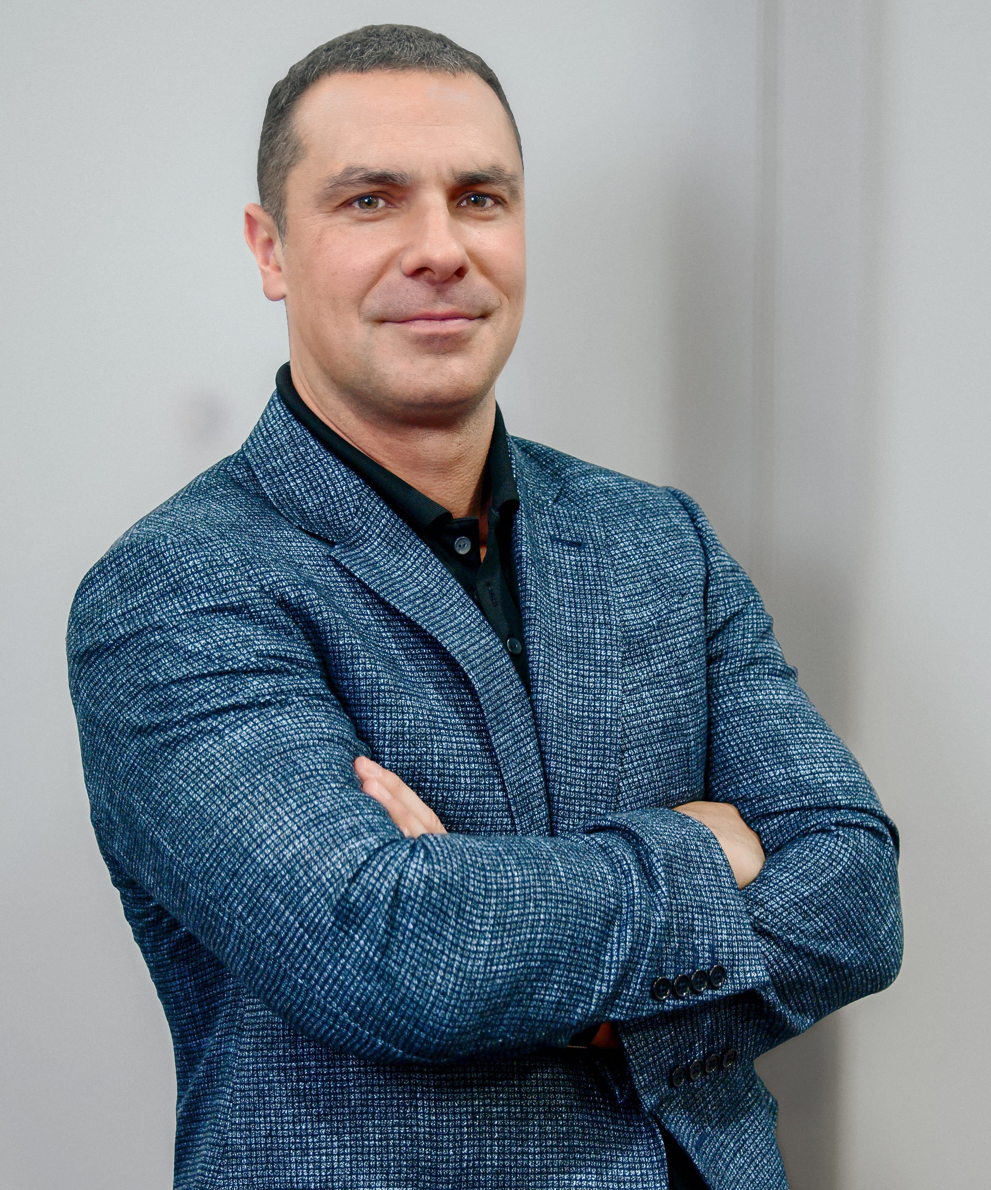Portrait of a man wearing a blue blazer with his arms crossed.